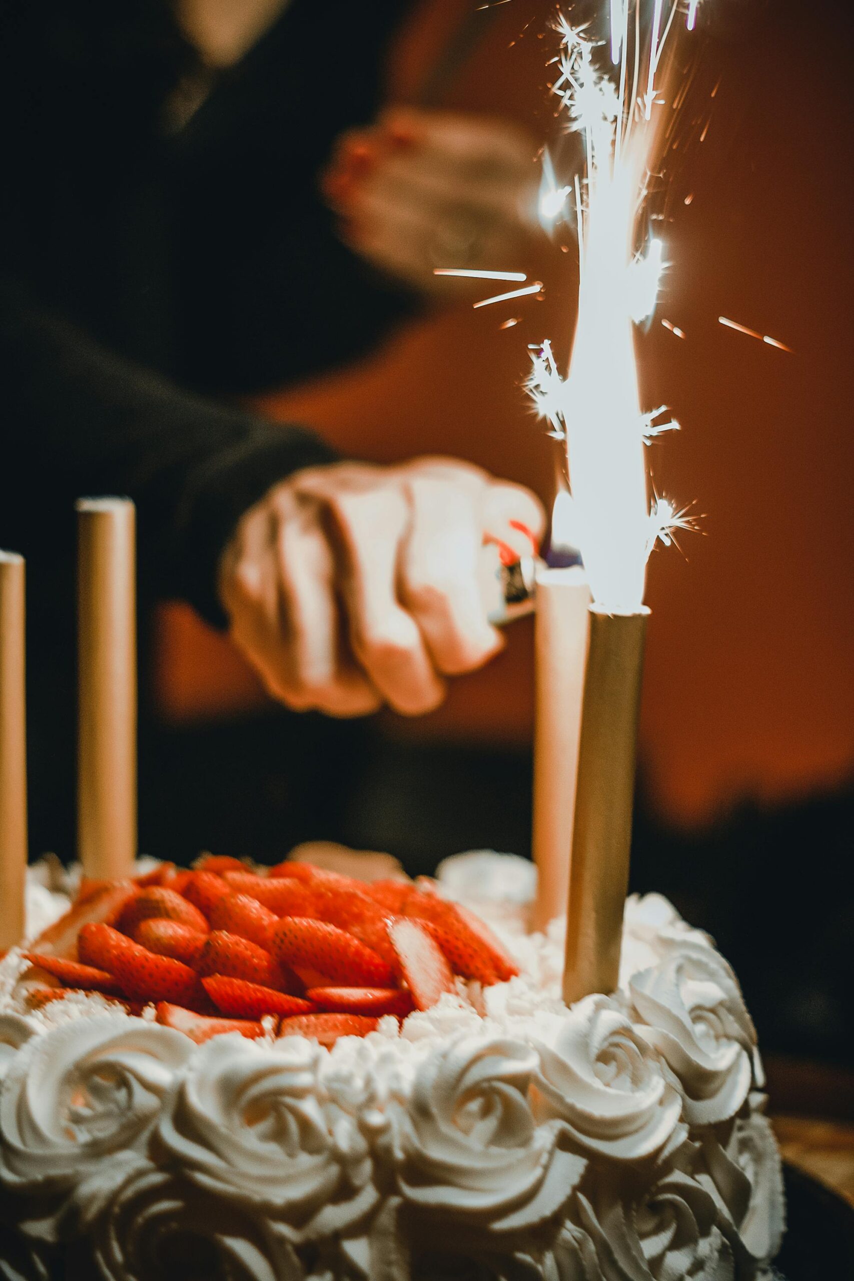 pexels-photo-1729797-1729797 A captivating image of a birthday cake adorned with lit sparklers and fresh strawberries.