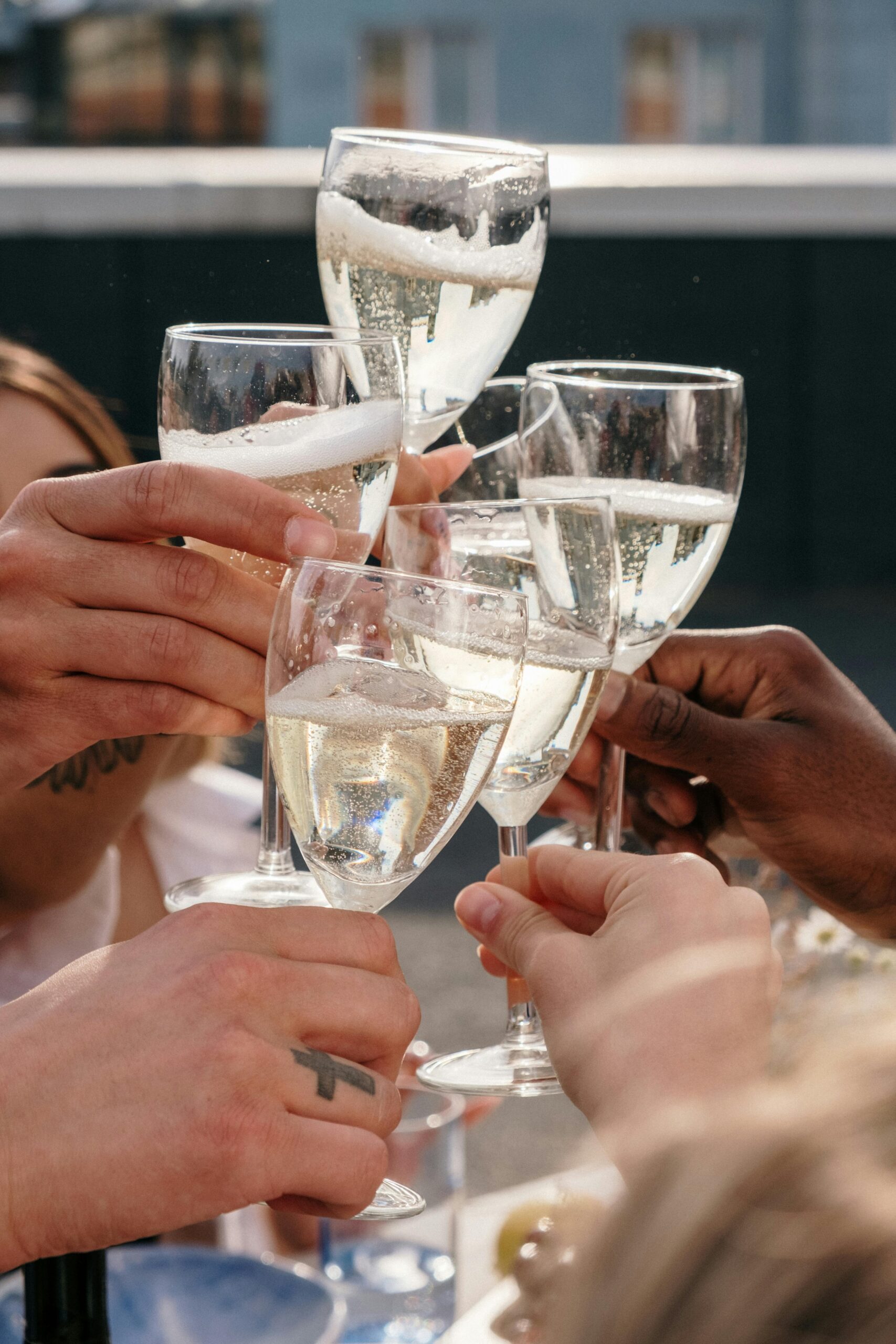 pexels-photo-4877867-4877867 Hands raising champagne glasses in a cheerful toast at an outdoor gathering.